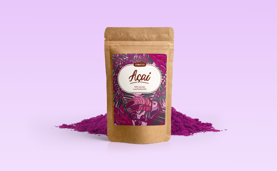 Photo of standing paper bag with label for Acai fruit powder. On the Label there is an illustration of an Acai palm tree and its fruits being eaten by a toucan, the color tone is purple-pink. Behind the bag is a pile of pinkish-purple powder for demonstration.