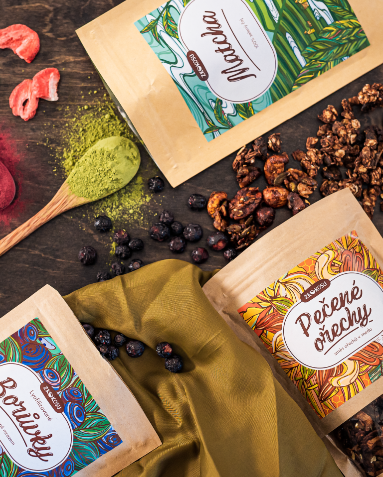 Photo of three bags with matcha tea, freeze dry blueberries and roasted nuts, shot from a perspective on a wooden board.