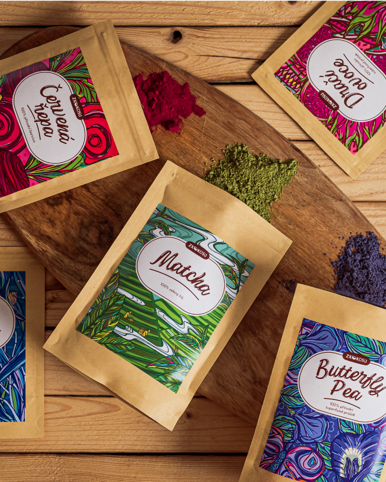 Photo of bags with colourful superfood powders of beetroot, butterfly pea, matcha tea and dragon fruit, shot from a perspective on a wooden board.